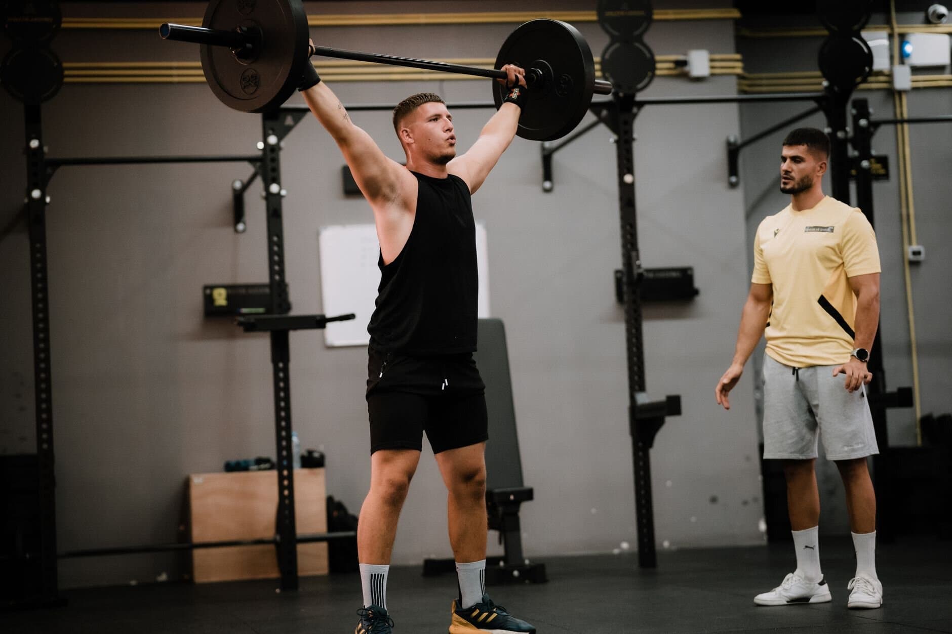 Coach watching a lifter press a barbell overhead