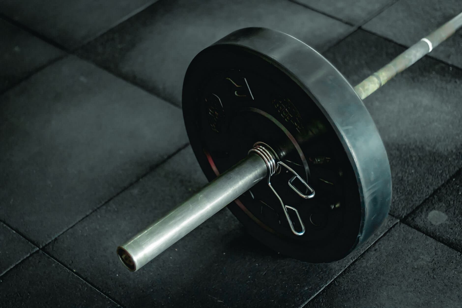 Loaded barbell resting on the gym floor between sets