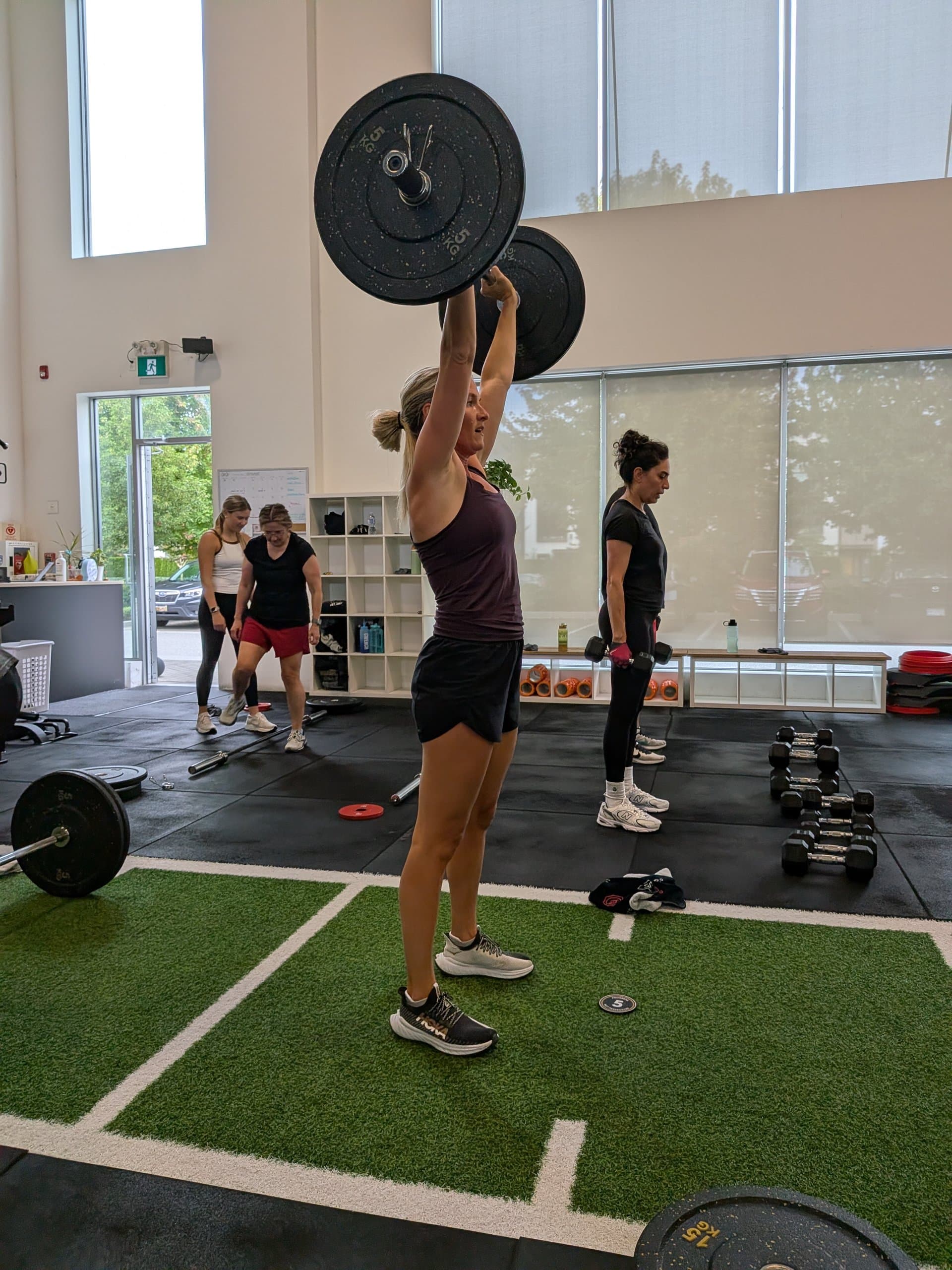 Member pressing a barbell overhead during a class at Build Fitness in Port Coquitlam