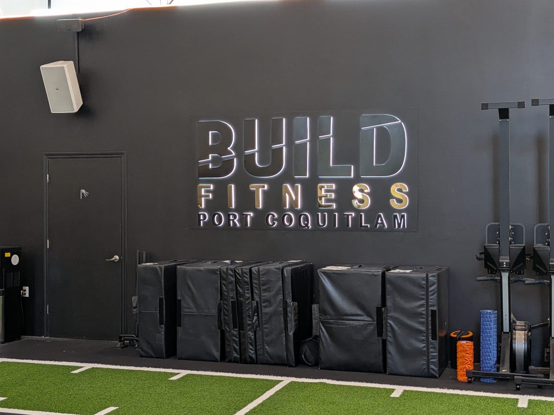 The BUILD FITNESS PORT COQUITLAM signage wall above the plyo boxes at Build Fitness in Port Coquitlam